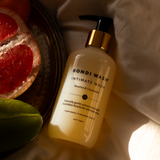 Bondi Wash intimate wash bottle with a plate of fruit in the background