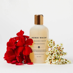 Bottle of Bondi Wash lingerie wash with red flowers and white flowers on a light background